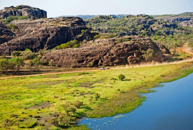Aerial view of a four wheel drive travelling along a dirt road surrounded by lush green grass and wetlands during a tour with Lords Kakadu & Arnhem Land Safaris, Arnhem Land, Northern Territory © Shaana McNaught