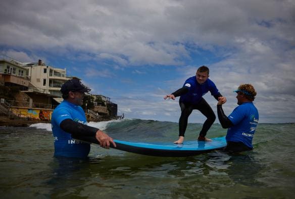 Man with a neurological disability surfing with instructors from Let's Go Surfing, Bondi Beach, Sydney, New South Wales © Tourism Australia