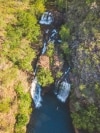 Aerial view over a person floating in a natural blue pool surrounded by trees with two large waterfalls cascading down at Florence Falls, Litchfield National Park, Northern Territory © Tourism NT/Dan Moore