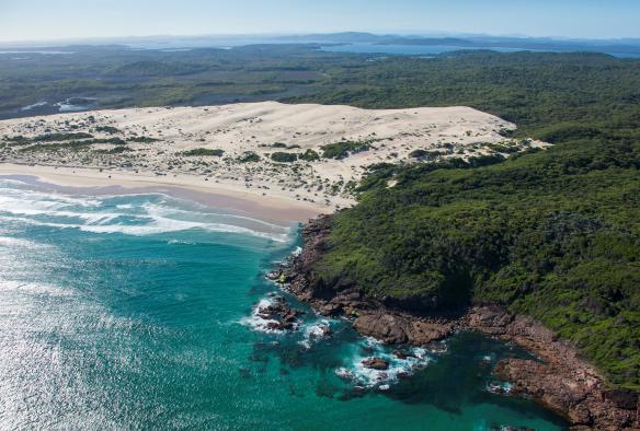 Aerial view over a white sand beach with turquoise water and green bushland at Samurai Beach, Port Stephens, New South Wales © Destination NSW