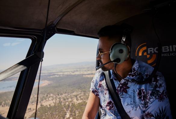 A person in a helicopter looking out over a landscape of Australian bushland, Grampians Helicopters, Grampians, Victoria © Tourism Australia 