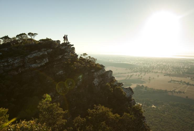 Two people standing on a rocky outcrop of a lush green mountain at Mount Sturgeon, Grampians, Victoria © Visit Victoria 
