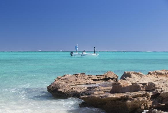 Hai người câu cá từ một chiếc thuyền trên biển màu ngọc lam, Ningaloo Fly Fishing, Thị trấn Exmouth, Tiểu bang Tây Úc © Tourism Australia