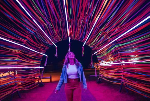 A woman walks through a colourful tunnel of light at Parrtjima Festival, Alice Springs, Northern Territory © Tourism NT