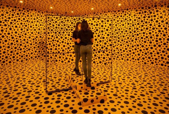 A woman stands in a room completely covered in orange with black dots at the National Gallery of Australia, Canberra, Australian Capital Territory © Tourism Australia