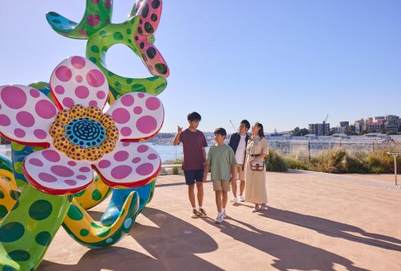 A family standing on a balcony beside a large flower sculpture covered in colourful dots at the Art Gallery of New South Wales, Sydney, New South Wales © Tourism Australia