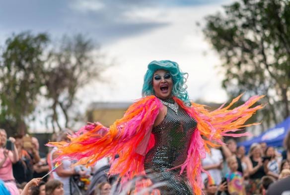 Một drag queen đang xoay tròn trên sân khấu ngoài trời với đông đảo khán giả cổ vũ buổi diễn, Lễ hội FabAlice, Thị trấn Alice Springs, Lãnh thổ phía Bắc © Tourism and Events NT/Helen Orr 