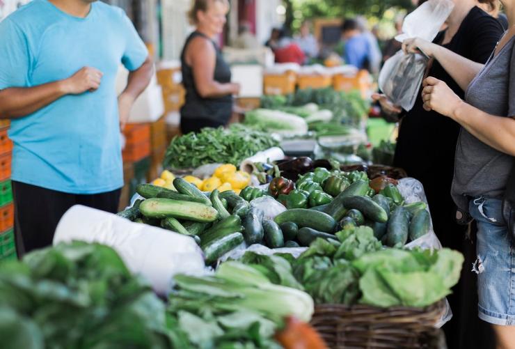 Close up of people gathered around a fresh produce stall with baskets of fruit and vegetables at Perth City Farm, Perth, Western Australia © Perth City Farm/Shoshana Kruger