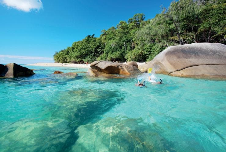Du khách đang lặn ống thở trong làn nước xanh trong và nông, bên cạnh một hòn đảo với bãi cát trắng và hàng cây, Đảo Fitzroy, Tiểu bang Queensland © Tourism and Events Queensland