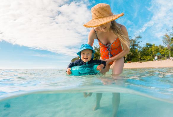 Một người mẹ và đứa con đang bơi trong làn nước xanh trong, phía sau là bờ đảo tại Đảo Green, Vùng nhiệt đới Bắc Queensland, Tiểu bang Queensland © Tourism and Events Queensland