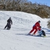 Two people with limited mobility adaptive skiing with instructors down a snow-covered mountain in Thredbo, Snowy Mountains, New South Wales © Tourism Australia