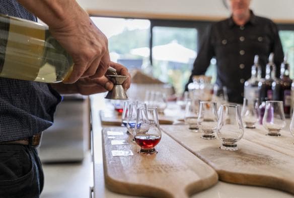 Closeup of bartender preparing tasting paddles of spirits at McHenry Distillery, Tasman Peninsula, Tasmania © Tourism Australia