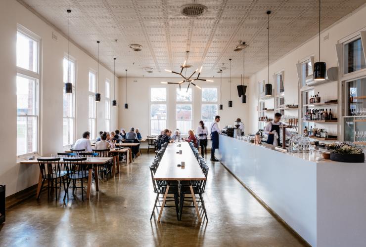 People dining in a light-filled venus with a long table down the centre Agrarian Kitchen Eatery, New Norfolk, Tasmania © Adam Gibson 