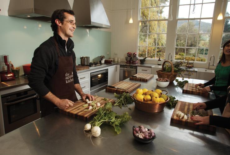 A chef smiling while speaking to guests over a table filled with fresh produce at Agrarian Kitchen Eatery, New Norfolk, Tasmania © Tourism Tasmania/Peter Whyte