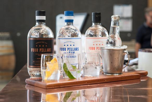 Dãy chai rượu gin đặt phía sau những chiếc ly được trang trí đẹp mắt trong buổi thử rượu tại Four Pillars Gin, Thung lũng Yarra, Tiểu bang Victoria © Four Pillars