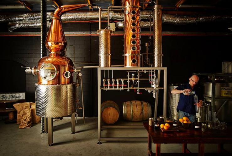 A person creating gin in a room filled with metal equipment at Four Pillars Gin, Healesville, Victoria © Visit Victoria