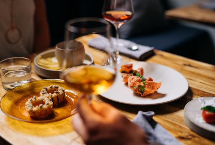 Plates of food and glasses of wine on the table at Dier Makr, Hobart, Tasmania © Osborne Images 