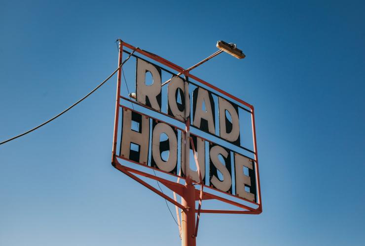 Angle looking up towards a sign reading "Road House" in a clear blue sky at Pink Roadhouse, Flinders Ranges & Outback, South Australia © South Australia Tourism Commission