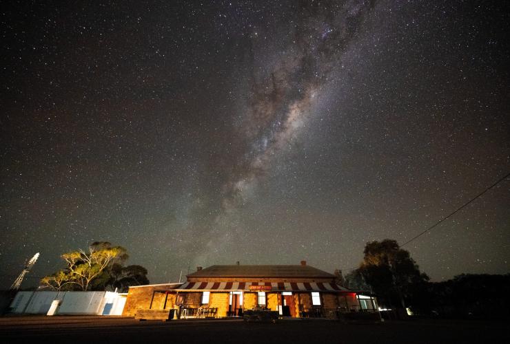 A building with a striped awning beneath a blanket of stars in the night sky at the Prairie Hotel, Flinders Ranges & Outback, South Australia © South Australia Tourism Commission
