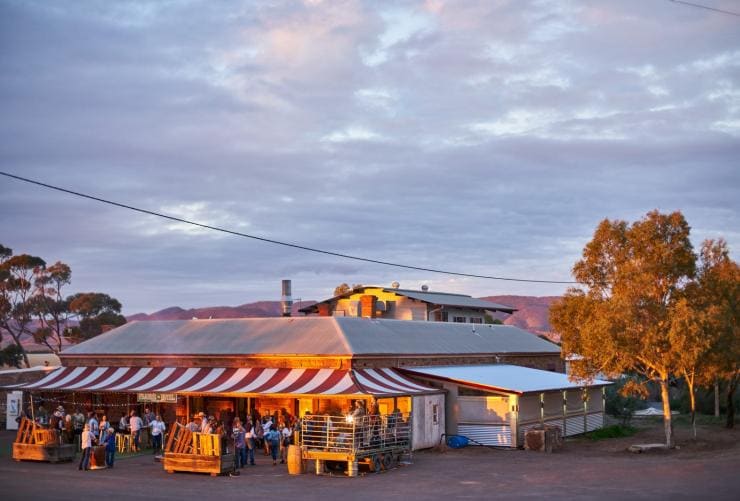 A crowd of people gathered outside an outback pub with a striped red and white awning at        Prairie Hotel, Flinders Ranges & Outback, South Australia © South Australia Tourism Commission/Tourism Australia