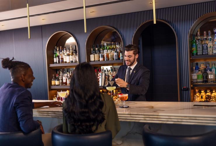 A couple sits at the bar while a bartender mixes cocktails at Aster, Sydney, New South Wales © Tourism Australia