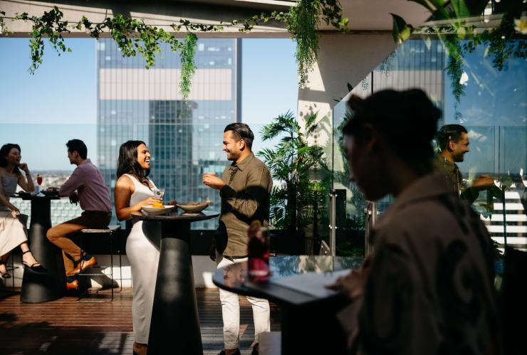 A couple enjoys the sunshine at Rooftop at QT, Perth, Western Australia © Tourism Australia 