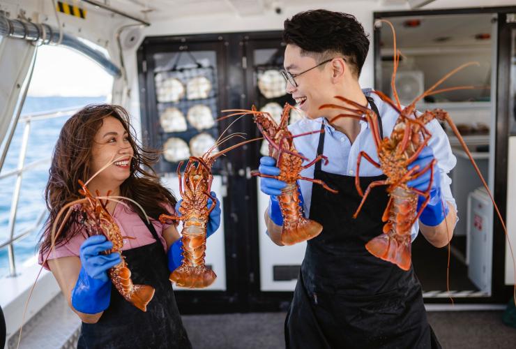 Two people holding lobsters aboard a boat with Rottnest Cruises, Rottnest Island, Western Australia © Tourism Australia
