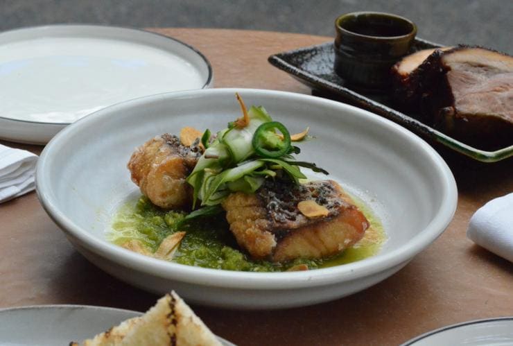 Cooked barramundi on a bed of greens topped with cucumber and jalapenos at The Smith, Melbourne, Victoria © The Smith