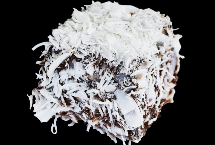 A Panna cotta lamington photographed on a black background at Flour & Stone, Woolloomooloo, New South Wales © Rodney Macuja and Australian Gourmet Traveller/Bauer Media