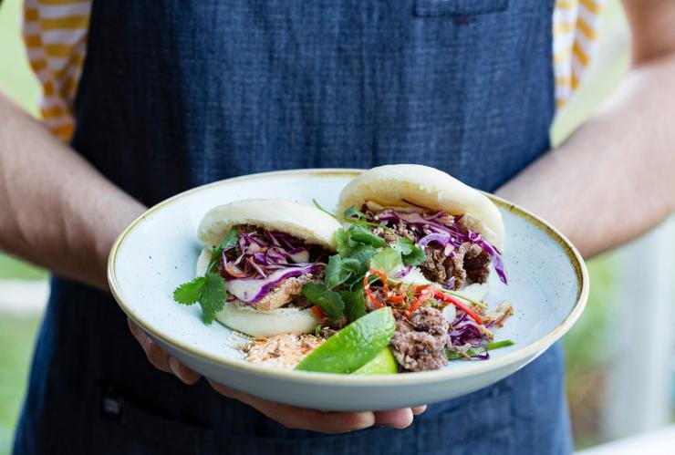 Một người đang cầm đĩa bánh bao kẹp hải sản, Nhà hàng Snapper Rocks, Thành phố Darwin, Lãnh thổ phía Bắc © Tourism NT