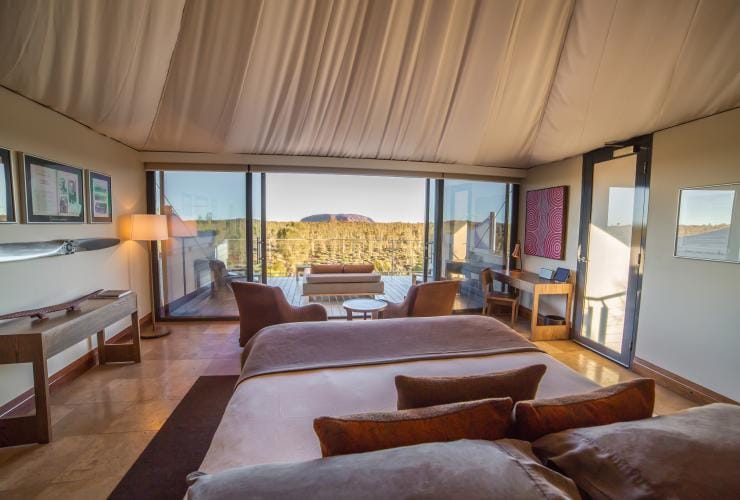 Interior of accommodation at Longitude 131, looking through windows at a private outdoor space with Uluru in the background in Yulara, Northern Territory © Baillie Lodges
