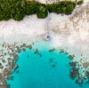 Aerial view over a cabana at the end of a jetty, stretching across white sand into clear blue water sprinkled with boulders on Haggerstone Island, Great Barrier Reef, Queensland © Tourism and Events Queensland