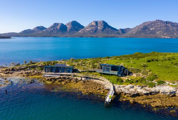 View over the water looking toward two buildings and a pier on the edge of Picnic Island, Coles Bay, Freycinet, Tasmania © Luke Tscharke