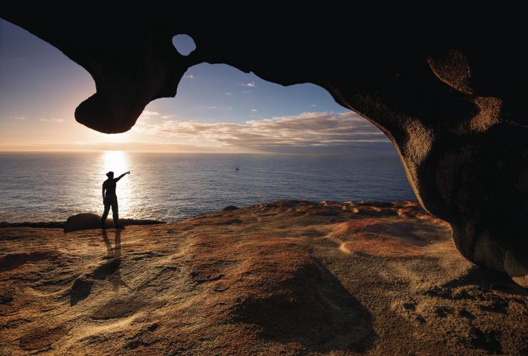 A person standing beneath the Remarkable Rocks pointing out towards the ocean, Kangaroo Island, South Australia © Julie Fletcher