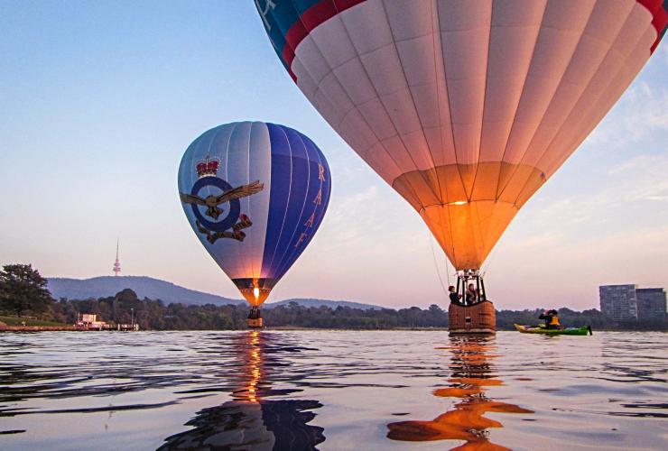 Hot Air Balloons landing on the still water of Lake Burley Griffin beside a person on a kayak, Canberra, Australian Capital Territory © Visit Canberra