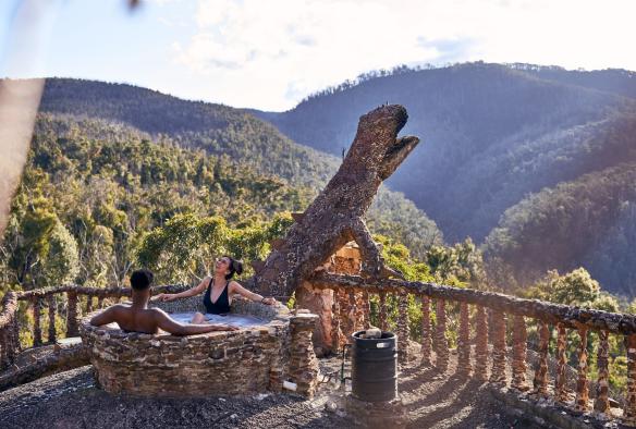 A couple in a hot tub with a view of forested mountains at Love Cabins, Blue Mountains, New South Wales © Destination NSW