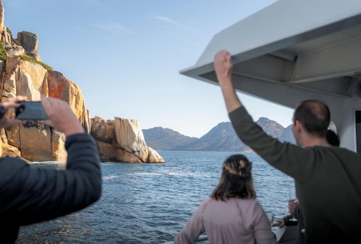 Guests on a scenic cruise admiring the rock formations around Wineglass Bay, Freycinet National Park, Tasmania © Tourism Australia