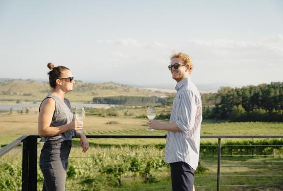 A couple share a glass of wine on the deck at Cubby and Co, Majura, ACT © Tourism Australia