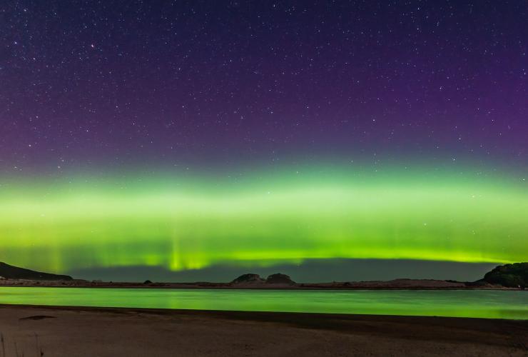The Aurora Australis lighting up the star filled night sky with vibrant green and purple along the South Coast Track, Tasmania © Matty Eaton