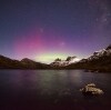 The Aurora Australis (Southern Lights) shining in purple and green hues behind the snow-capped peaks of Cradle Mountain-Lake St Clair National park, Tasmania © Pierre Destribats