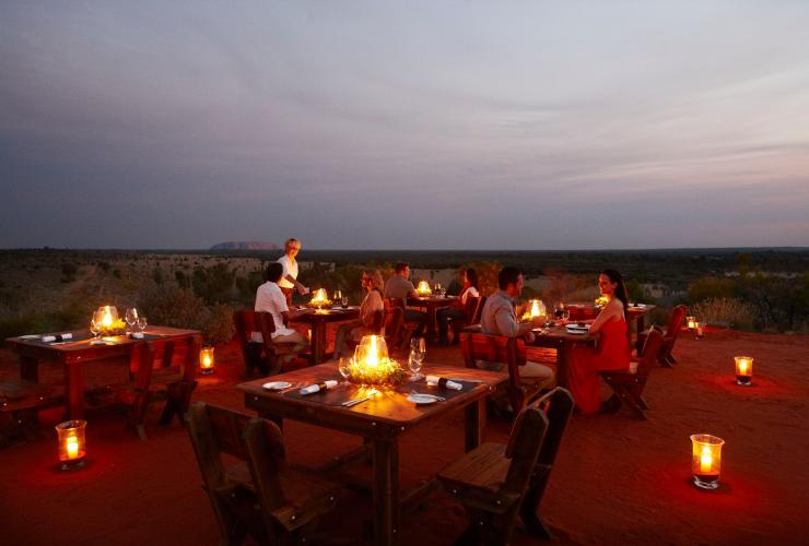 Guests outdoor dining at candlelit tables with Uluru in the background at Tali Wiru, Uluru-Kata Tjuta National Park, Northern Territory © Tali Wiru