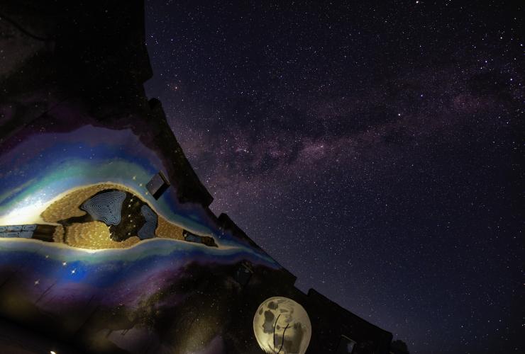 A wall filled with Aboriginal paintings of the night sky and native animals beside a view of the starry night sky at Perth Observatory, Bickley, Western Australia © Perth Observatory/Matt Woods