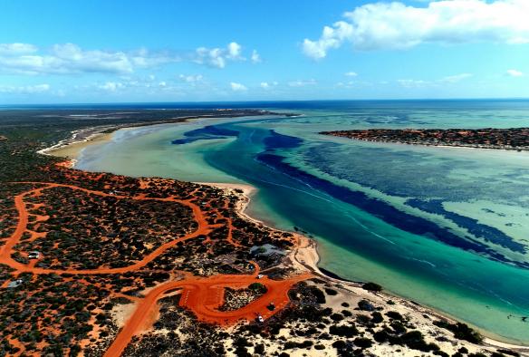 Ảnh chụp từ trên cao làn nước xanh cuộn xoáy của Đầm phá Big Lagoon bao quanh bởi cát đỏ và thảm thực vật tại Khu di sản thế giới Vịnh Shark, Tiểu bang Tây Úc © Australia’s Coral Coast