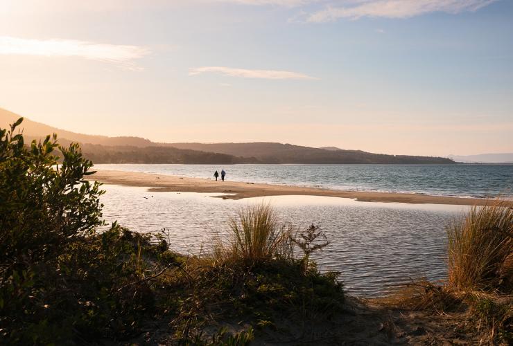 Two people strolling along the sand beside the ocean at Adventure Bay during sunset, Bruny Island, Tasmania © Tourism Australia