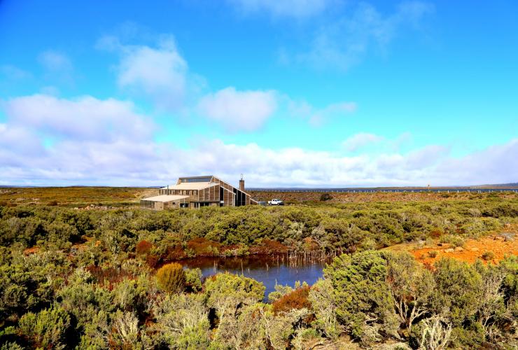 The exterior of Thousand lakes lodge, tucked amid a field of trees and shrubbery beside a small lake in the Central Highlands, Tasmania  © Alice Hansen