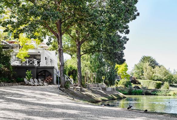 Một tòa nhà lớn bên bờ hồ bao quanh là cây cối xanh mướt, Lake House, thị trấn Daylesford, tiểu bang Victoria © Visit Victoria