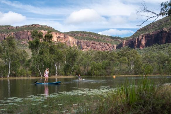 Gia đình chèo thuyền kayak và ván chèo đứng, bên cạnh những ngọn núi phủ đầy cây bụi, Mt Mulligan Lodge, thị trấn Mount Mulligan, Tiểu bang Queensland © Tourism and Events Queensland