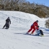 Two people with limited mobility adaptive skiing with instructors down a snow-covered mountain in Thredbo, Snowy Mountains, New South Wales © Tourism Australia