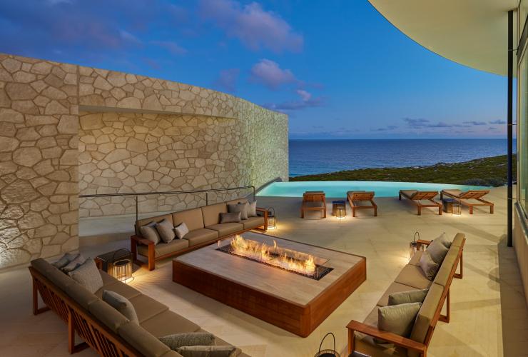 A balcony with lounges surrounding a fire pit, deck chairs lining a small pool and sweeping views of the ocean beyond during dusk at Southern Ocean Lodge, Kangaroo Island, South Australia © George Apostolidis Photography