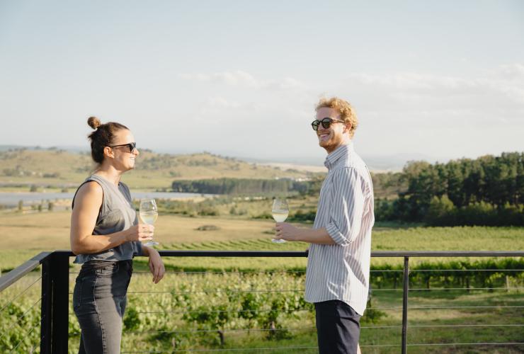 Hai người đang nhâm nhi rượu vang trên ban công nhìn ra vườn nho, The Naked Cubby Co, Mount Majura Vineyard, Lãnh thổ Thủ đô Úc © Tourism Australia